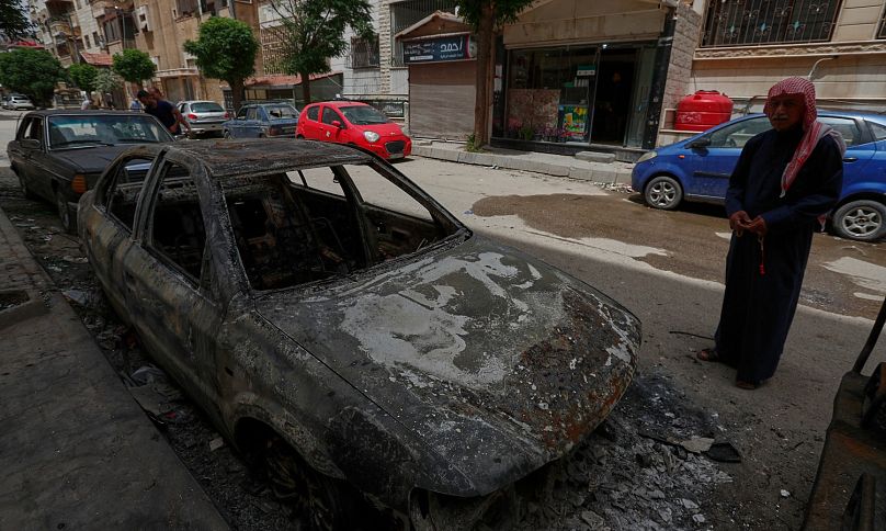 رجل يتفقد سيارة متفحمة احترقت بعد اندلاع اشتباكات بين أفراد من الطائفة الدرزية ومقاتلين موالين للحكومة في بلدة صحنايا جنوب دمشق في سوريا الخميس 1 مايو 2025.