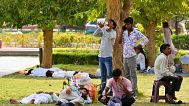 A person drinks water as other rest under the shade of trees as the city continues in the grip of a heatwave, in Delhi, India, 18 June 2024. 