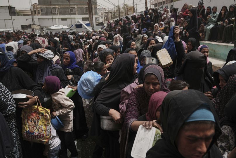 فلسطينيون يتسلّمون مساعدات غذائية في مخيم النصيرات وسط قطاع غزة، يوم الأربعاء 30 أبريل 2025. 
