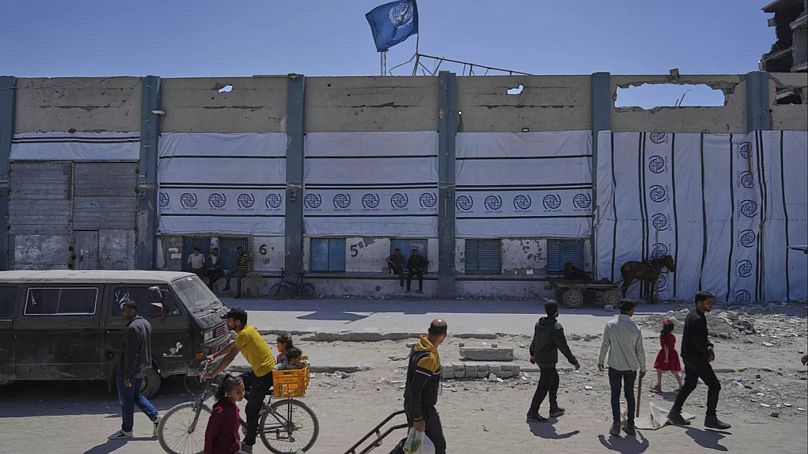 فلسطینیان در حال عبور از کنار مرکز توزیع کمک‌های بشردوستانه آژانس امداد سازمان ملل در غزه (جبالیا)