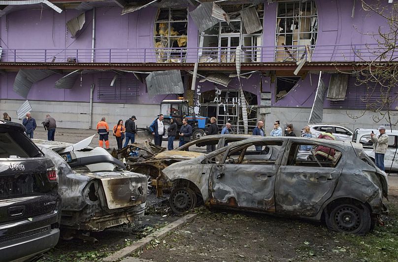 Belediye çalışanları, Rusya'nın Kiev'de gerçekleştirdiği drone saldırısının ardından yerleşim bölgesindeki yanmış arabaların yakınında temizlik yapıyor, 4 Mayıs 2025.