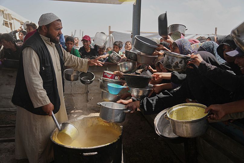 Des enfants et des femmes palestiniens luttent pour obtenir de la nourriture dans une cuisine communautaire à Khan Younès, dans la bande de Gaza, le samedi 3 mai 2025