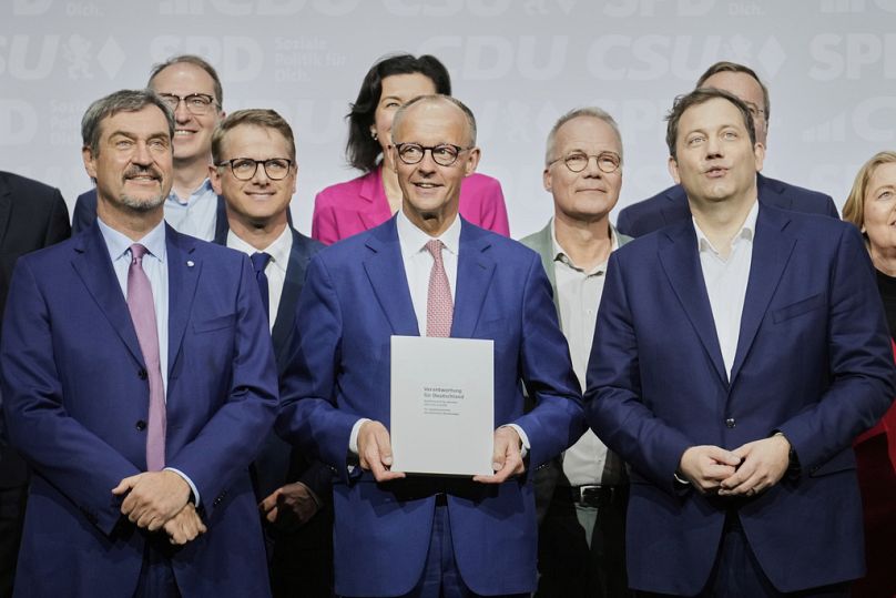 Einen Tag vor seiner Kanzlerwahl: Friedrich Merz hält gut gelaunt den Koalitionsvertrag in den Händen.