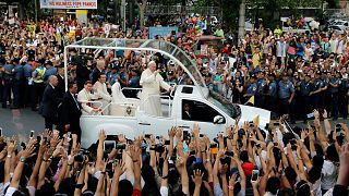 Pope Francis waves to onlookers from his popemobile as his motorcade passes through Manila, 16 January, 2015
