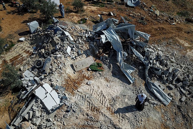 Des femmes palestiniennes se tiennent à côté des décombres de leur maison démolie par Israël à Khirbet Ma'in, dans la région de Masafer Yatta, le 25 janvier 2025
