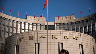 A woman walks past the headquarters of the People's Bank of China in Beijing, Friday, March 10, 2017. 