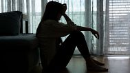 A distressed woman sits in the dark.