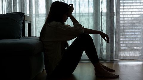 A distressed woman sits in the dark.