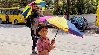 A woman and her children returning from school hold umbrellas as protection from the sun during severe heat in the northern Indian state of Uttar Pradesh, 25 April 2025.
