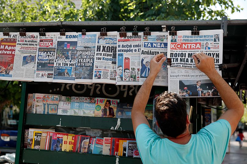 A vendor adjusts the front pages of the Greek newspapers as all of them refer to the election result in Athens, 8 July, 2019