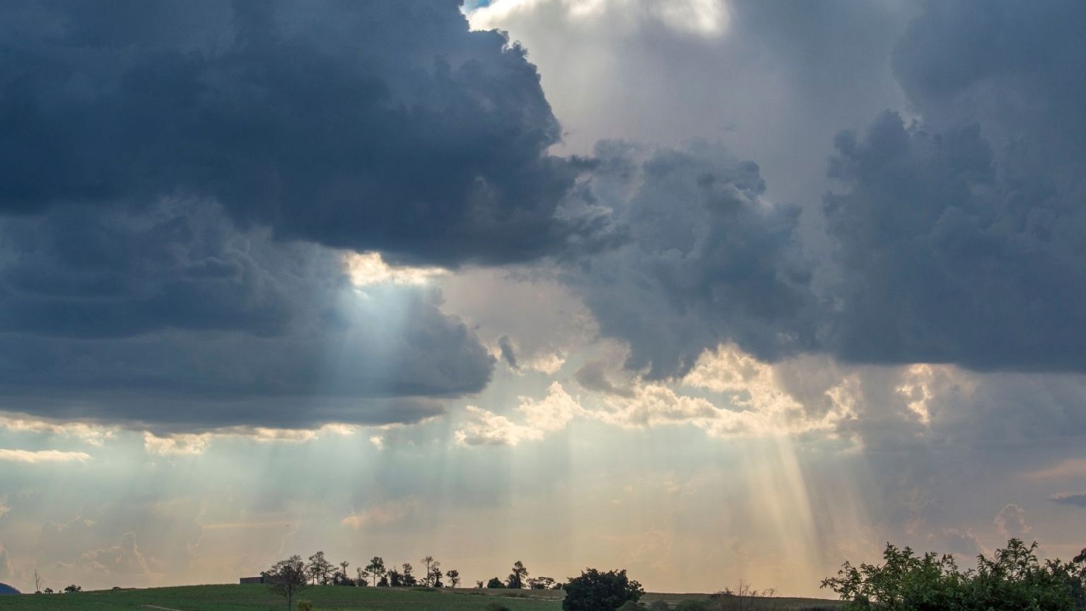 A cloudy sky with rain and sun beams.