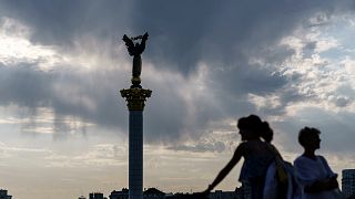 The sun sets behind the Independence Monument overlooking Maidan Square on the country's National Flag Day, Tuesday, Aug. 23, 2022, in Kyiv, Ukraine.