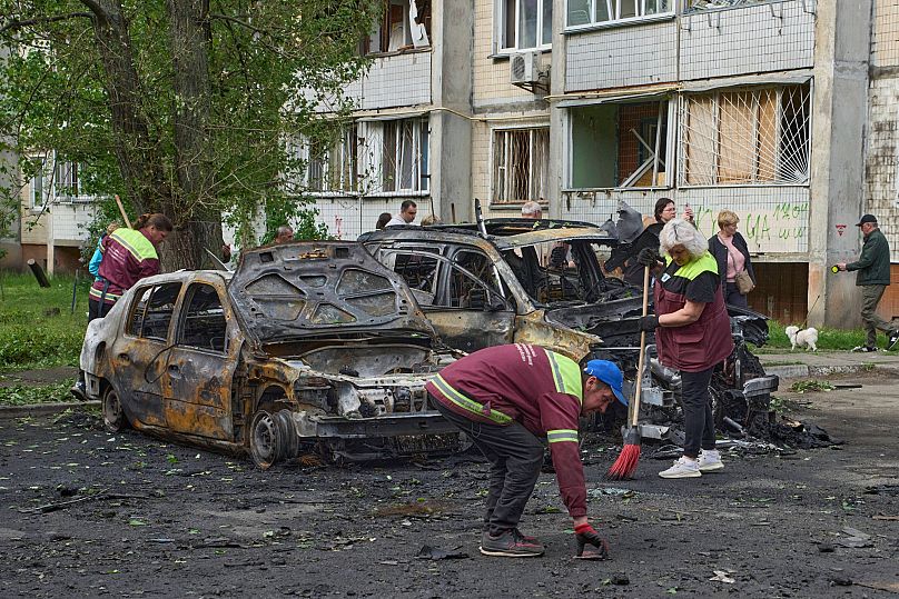 Archivo: Trabajadores municipales limpian en torno a los coches quemados en una zona residencial tras un ataque ruso con drones en Kiev, el 4 de mayo de 2025.