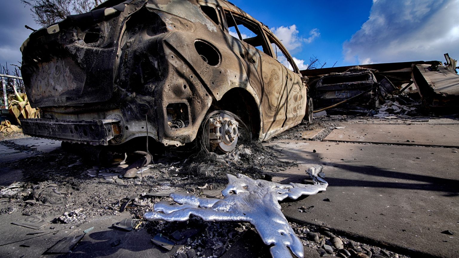 Melted metal and burned out cars sit destroyed in a driveway of a home burned by the wildfire that spread through the Pacific Palisades neighborhood of Los Angeles.