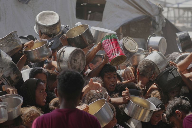 فلسطينيون يحاولون الحصول على طعام تبرعت به جهات خيرية في مطبخ مجتمعي بخان يونس جنوب قطاع غزة، 9 مايو 2025.