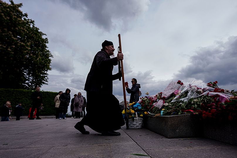 Ksiądz niesie ikonę pod pomnikiem Nieznanego Żołnierza na pomniku weteranów II wojny światowej podczas ceremonii z okazji 80. rocznicy Dnia Zwycięstwa w Europie, Kijów
