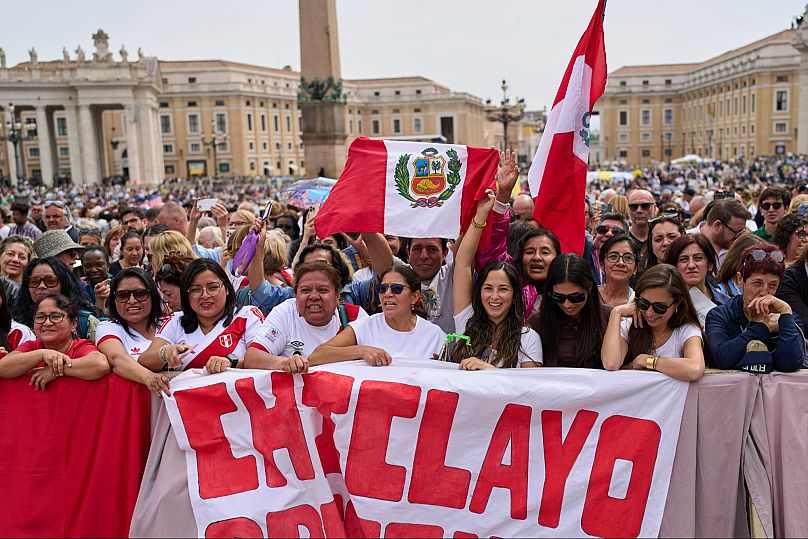 Faithful from Chiclayo, Peru, wave flags as Pope Leo XIV appears at St. Peter's Basilica for his first Sunday blessing after his election