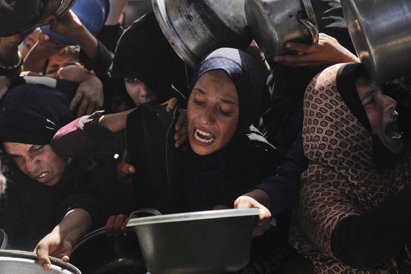 Palestinians struggle to obtain donated food at a community kitchen in Khan Younis, in the southern Gaza Strip, Friday, May 9, 2025