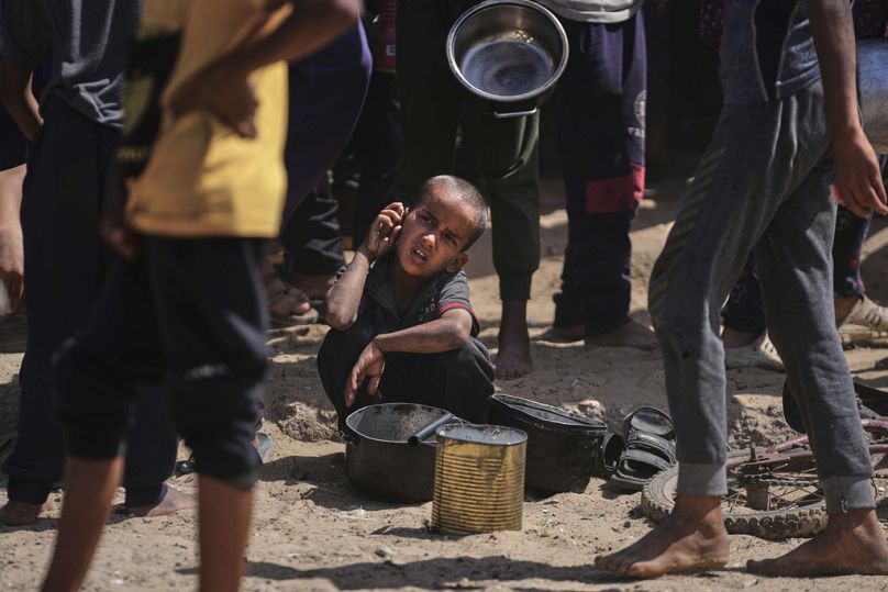 A Palestinian child rests while struggling to obtain donated food at a community kitchen in Khan Younis, in the southern Gaza Strip, Friday, May 9, 2025
