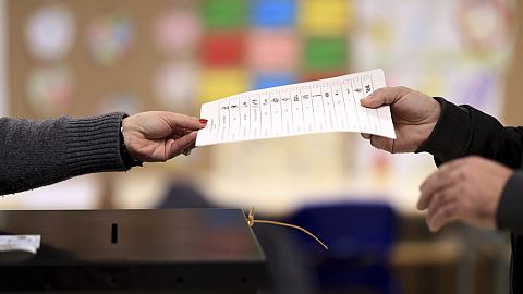 A man holds a list of candidates before casting his vote at a polling station in Espinho, northern Portugal, on Sunday, March 10, 2024.
