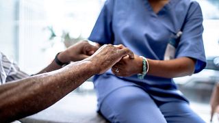 A nurse holds a patient's hands.