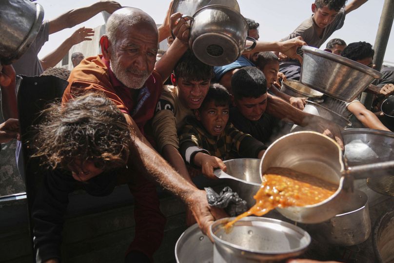فلسطينيون يكافحون للحصول على الطعام في مطبخ جماعي بخان يونس في قطاع غزة، الأحد 11 أيار/مايو 2025. 