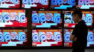Un homme regarde le discours du Premier ministre indien Narendra Modi sur des écrans de télévision dans un centre commercial après l'opération "Sindoor" à Bombay, en Inde.