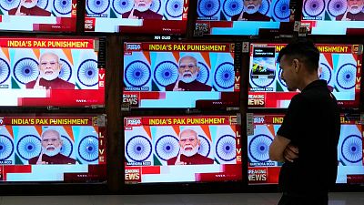Un homme regarde le discours du Premier ministre indien Narendra Modi sur des écrans de télévision dans un centre commercial après l'opération "Sindoor" à Bombay, en Inde.