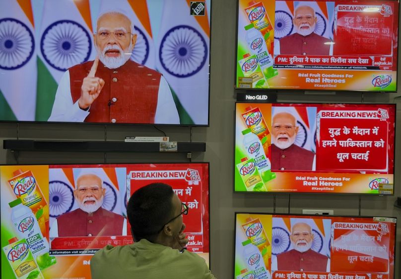 Um homem indiano assiste à transmissão em direto do discurso do primeiro-ministro indiano Narendra Modi na segunda-feira, 12 de maio de 2025. 
