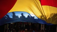 People cast shadows on a Romanian flag during an electoral rally of presidential candidate Nicusor Dan, a week ahead of the second round of the country's presidential election