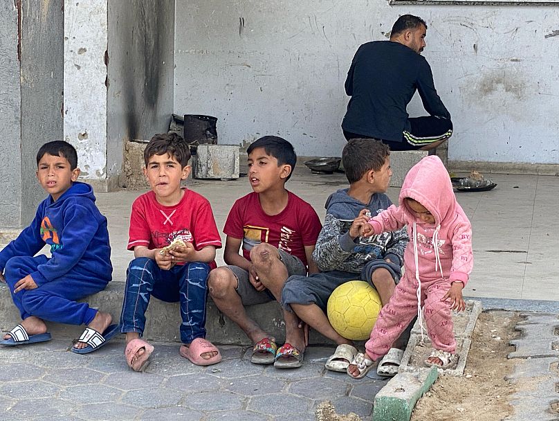 أطفال بنتظرون تعبئة المياه في دير البلح بتاريخ 14 مايو أيار 2025