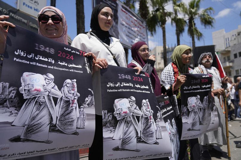 نساء فلسطينيات يحملن لافتات  لإحياء ذكرى يوم النكبة، في مدينة رام الله بالضفة الغربية، يوم الأربعاء، 15 مايو 2024