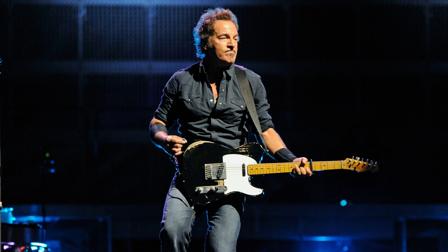 In a blue-hued spotlight, Springsteen delivers an electrifying performance with a message of defiance.