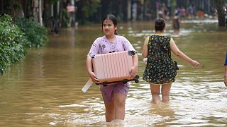 People carrying belongings wade in flooded street in the aftermath of Typhoon Yagi, in Hanoi, Vietnam on 12 September 2024. 