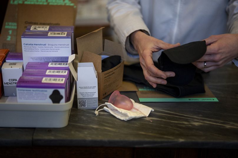 Uma farmacêutica prepara uma roupa interior para a menstruação ao lado de outros artigos gratuitos, numa farmácia em Barcelona, Espanha, terça-feira, 5 de março de 2024. 