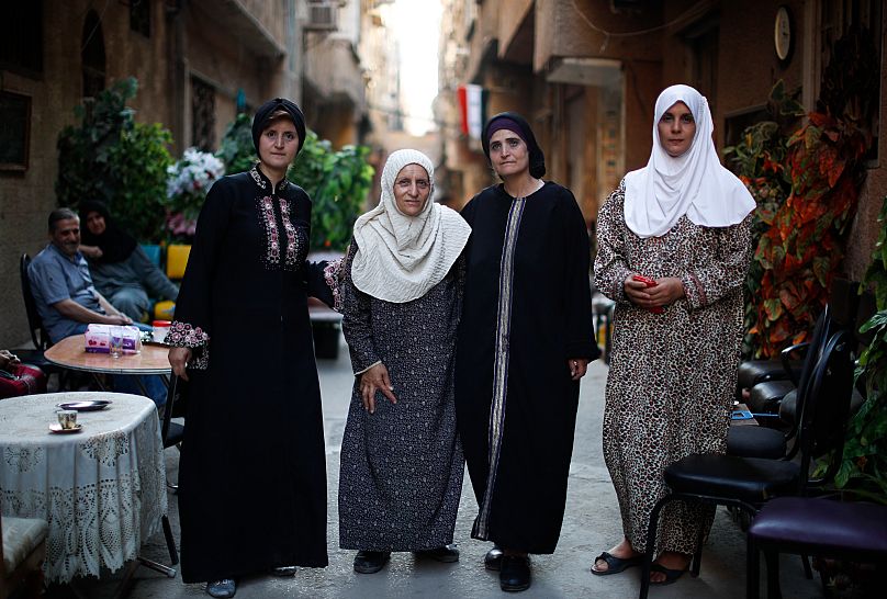 3 شقيقات فلسطينيات من اليمين إلى اليسار، أمل، حنان، ازدهار، ميسرة، يقفن لالتقاط صورة خارج منزلهن في شارع اللد في مخيم اليرموك للاجئين الفلسطينيين في دمشق. 16 تموز 2018