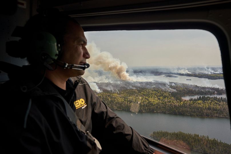 Le Premier ministre du Manitoba, Wab Kinew, observent les feux de forêt qui brûlent dans le nord de la province depuis un hélicoptère, le mardi 14 mai 2024