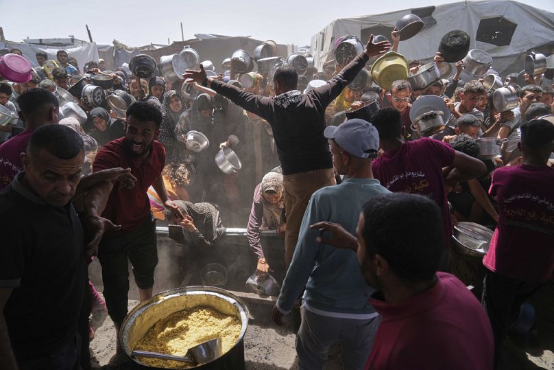 فلسطينيون يحاولون الحصول على مساعدات غذائية من مطبخ مجتمعي في خان يونس، جنوب قطاع غزة، 16 أيار/مايو 2025.