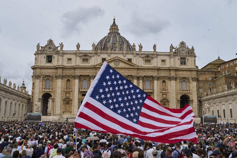  A US flag in the crowd as Pope Leo XIV appears at the central balcony of St. Peter's Basilica for his first Sunday blessing.