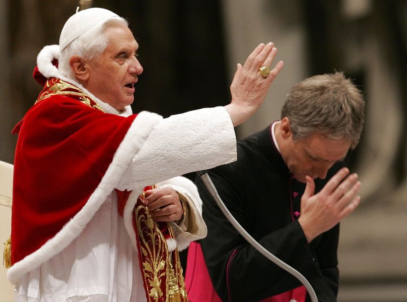  Pope Benedict XVI blesses as his personal assistant, the Rev. Georg Gaenswein, makes the sign of the cross at the end of the candle Mass.