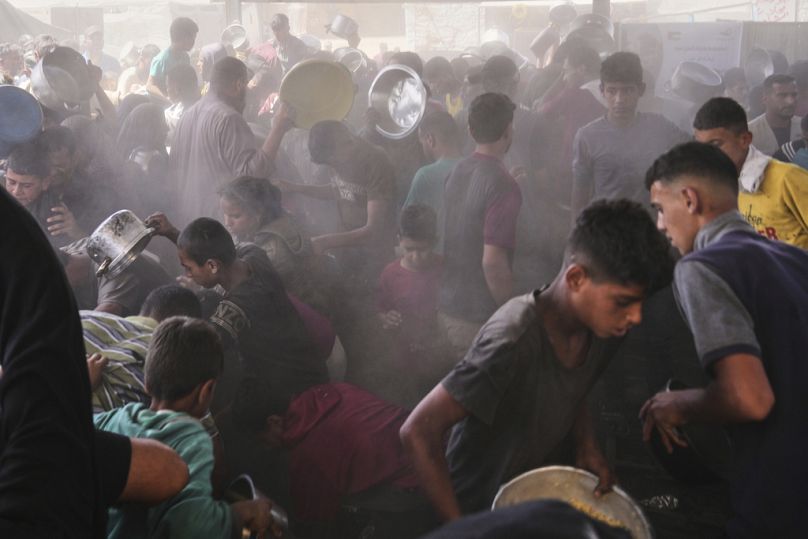 فلسطينيون يحاولون الحصول على مساعدات غذائية في خان يونس، جنوب قطاع غزة، يوم الجمعة 16 أيار/ مايو 2025. 