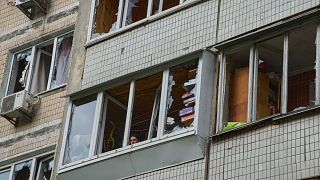 FILE: A resident looks out of the broken window in an apartment house following Russia's drone attack in Kyiv, 4 May 2025