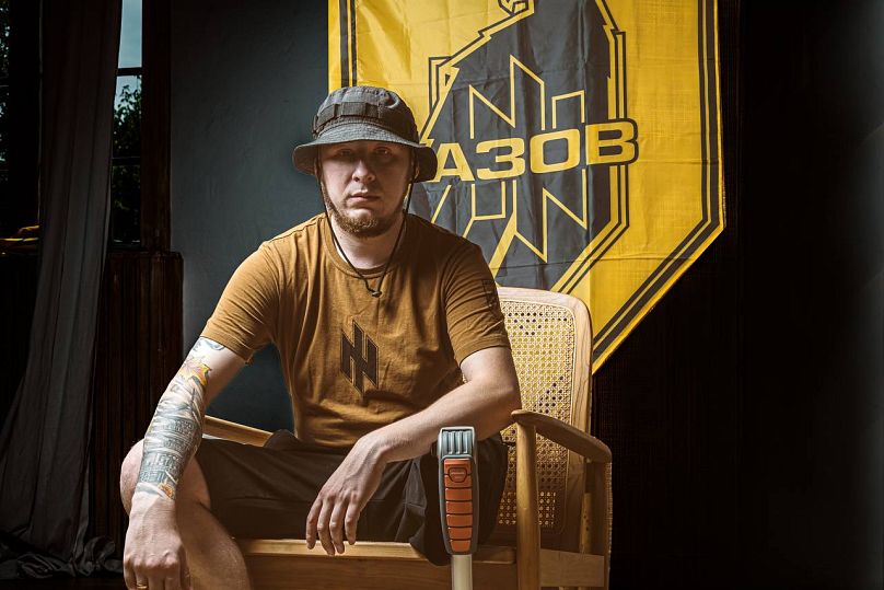 Anatolii Basenko sitting in front of an Azov-flag.