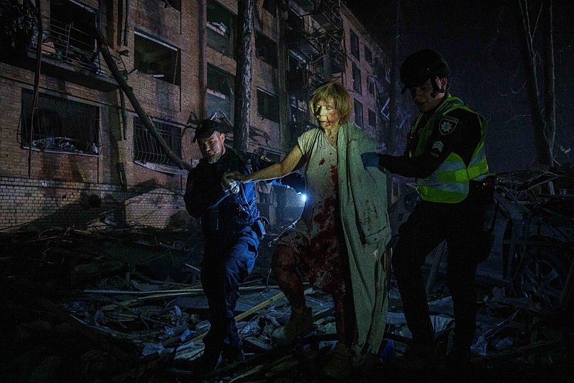 Police officers help an injured woman leave her house after a Russian air strike in Kyiv, 24 April, 2025
