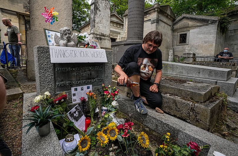 A fan pours some whiskey on the tomb of Jim Morrison at the Pere-Lachaise cemetery in Paris - 2021