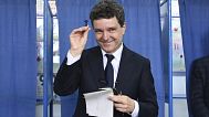 Presidential candidate Nicusor Dan smiles while holding a stamp before casting his ballot in the second round of the country's presidential election redo in Fagaras, Romania, 