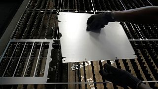 A worker lifts a steel sheet after cutting it in a specific design at a factory in a suburb of Bengaluru, India.
