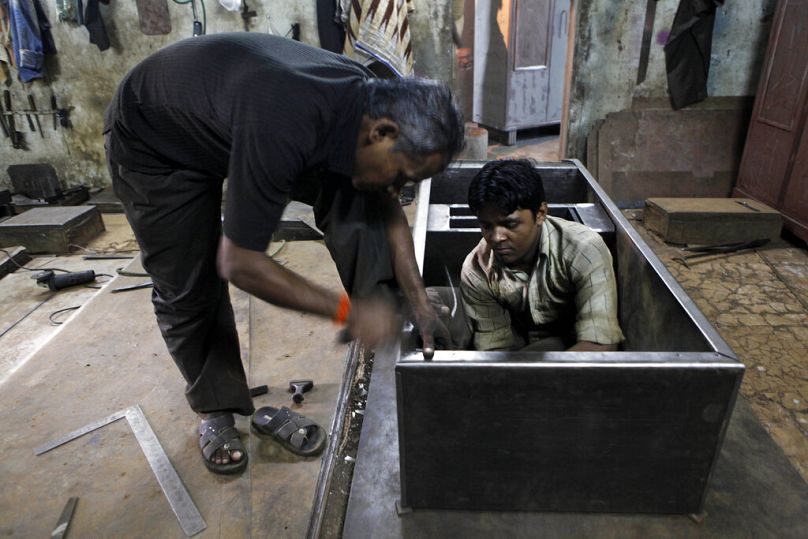 Um trabalhador indiano martela um armário de aço numa fábrica de armários metálicos em Mumbai, Índia, sexta-feira, 12 de outubro de 2012. 