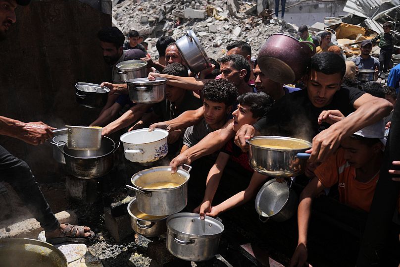 Palestinians struggle to get donated food at a community kitchen in Jabalia, 19 May, 2025