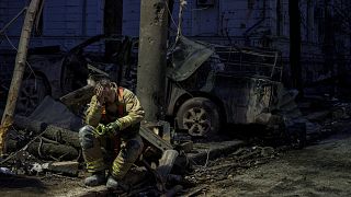 A rescue worker rests near university building destroyed by a Russian missile strike on Sumy, 13 April, 2025